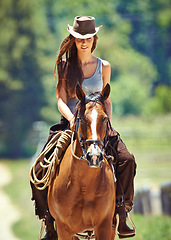 Image showing Woman, cowgirl and horse riding in the countryside for journey, travel or outdoor adventure in nature. Female person or western rider with hat, saddle and animal stallion at ranch, farm or stable