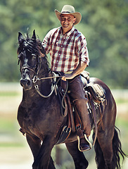 Image showing Portrait, cowboy and man riding horse with saddle on field in countryside for equestrian or training. Nature, summer and smile with mature horseback rider on animal at ranch outdoor in rural Texas