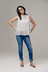 Image showing Happy, woman and portrait for fashion style in denim jeans on a gray studio background. Female person, brunette or adult with casual clothing, glasses or stylish outfit in confidence on mockup space