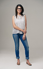 Image showing Happy woman, portrait and fashion with glasses, denim jeans or style on a gray studio background. Female person, brunette or adult with casual clothing or stylish outfit in confidence on mockup space