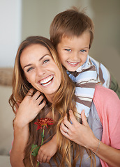 Image showing Portrait, mother and son with smile on piggyback for mothers day, bonding and together inside. Happy woman, boy and laugh with flower, hug and love for playful weekend in family home New Zealand