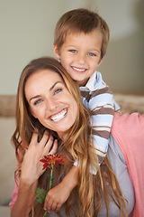 Image showing Portrait, mother and son with smile on mothers day with piggyback, bonding and together inside. Happy woman, boy and laugh with flower, hug and love for playful weekend in family home in Canada