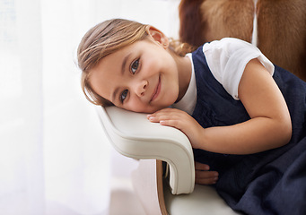 Image showing Girl, child and portrait with rest on chair in living room of home for relax, break and smile with confidence. Young person, kid and face or happy in lounge for wellness, holiday and weekend vacation