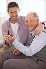 Image showing Dad, adult son and medal for gift, support and congratulations with celebration and bonding at home. Men in portrait in lounge, family time with reward or award for present, happiness and gratitude