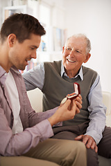 Image showing Father, adult son and medal as present special event or birthday celebration with family heirloom for love and bonding. Men at home, gift giving and happiness with surprise, gratitude and thanks