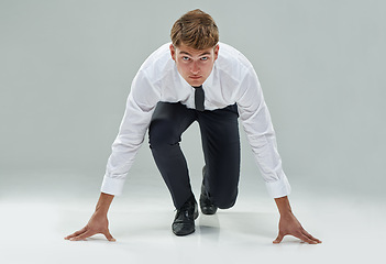 Image showing Portrait, competitive businessman and starting position on studio background to chase deadline, target or deal in business. Male model, corporate person or lawyer in running pose to race or challenge