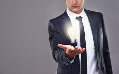 Image showing Business man, light bulb glow and ideas for entrepreneur with innovation and problem solving for energy saving. Hologram, solution and corporate goals for knowledge and power on grey background