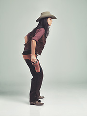 Image showing Woman, cowgirl and weapon in studio, clothing for wild west gun, outfit and halloween costume with holster. Female person, cowboy hat and boots from Texas, white background and dress up like bandit