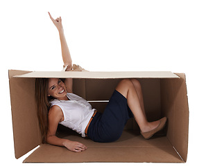 Image showing Portrait, space and pointing with woman in box for studio marketing, isolated or white background for advertising. Smile, hole and hand gesture for breakthrough with happy young person showing mockup