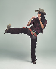 Image showing Cowgirl, kick and fight with fists in studio for western character, wild west outfit and hat for sheriff. Female person, costume and angry with aggression, rage and isolated with grey background