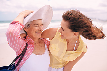 Image showing Senior, mother and woman with beach wind or vacation bonding on tropical island or holiday, happiness or retirement. Old person, daughter and hat at Florida seaside or travel tourism, relax or trip