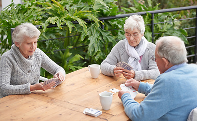 Image showing Elderly people, card games and coffee at table with outdoor background for retirement and old age. Group, seniors or family with beverages and thinking for poker, relax and break together on patio