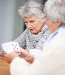 Image showing Senior women, thinking and playing cards with game for friends in retirement, relax and bonding together. Elderly people, poker and strategy with serious fun at table in nursing home for weekend.