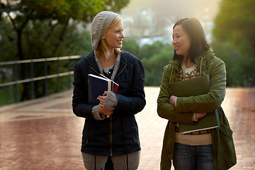 Image showing Students, women and friends on campus for university, conversation while walking to class and smile outdoor. College, communication and books for studying, education and academic growth with talk
