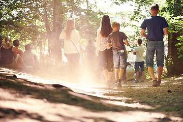 Image showing Festival, party and family walking in forest outdoor together for event, celebration or social gathering. Mother, father and children in nature, park or woods for summer entertainment from back