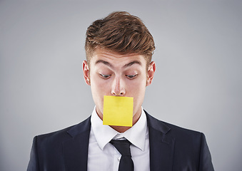 Image showing Business man, sticky note and mouth in studio for silence, reminder and thinking by white background. Person, employee or corporate workout with paper on lips for compliance, censorship and quiet