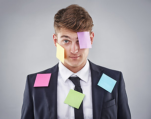 Image showing Business man, overwhelmed and sticky note on face, suit or clothes in studio portrait by background. Person, employee or corporate staff with paper, reminder or ideas for schedule, meeting or report