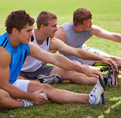 Image showing Group, men and field for stretching legs on ground for warm up, workout and training together in nature. Sports, people and exercise on lawn for health, wellness and fitness on grass with friends