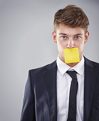 Image showing Business man, sticky note and mouth in portrait for silence, reminder and studio by white background. Person, employee and corporate workout with paper on lips for compliance, censorship and quiet