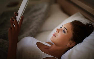 Image showing Woman, tablet and bed at night, scrolling and entertainment with tech and relaxing for peace before sleep. Female person, browsing and online for home, internet and elearning or social media