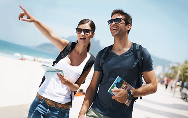 Image showing Couple, holiday and pointing with map at beach as tourist in summer, trip and smile for adventure in Brazil. Directions, relationship and bonding on vacation in seaside for travel, break and happy