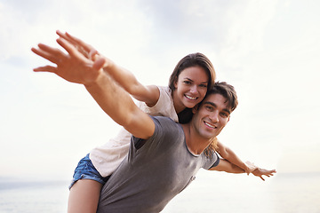 Image showing Couple, beach and piggyback with freedom, smile and nature with travel and date for relationship. Man, woman and indonesia sea for adventure, vacation and tropical holiday with sunshine and portrait