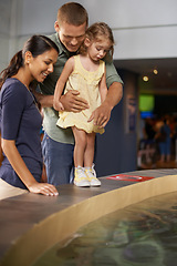 Image showing Happy family, little girl and aquarium with water for sightseeing, travel or tour at the zoo. Mother, father and child or kid looking at sea creature, fish or explore exhibit for bonding or holiday