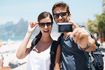 Image showing Couple, beach and camera for selfie on vacation with smile, sunglasses and outdoor for memory in summer. People, man and woman with photography by ocean for journey, vacation and sunshine in Italy