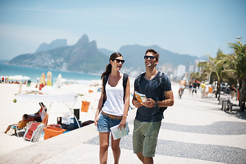 Image showing Couple, tourist and walk in beach with map on holiday in summer, trip and happy in Brazil. Relationship, vacation and bonding in seaside for summer with adventure, travel and smile for break.