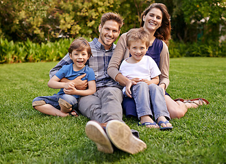 Image showing Smile, nature and portrait of children with parents relaxing on grass in outdoor park or garden. Happy, love and boy kids sitting on lawn with mother and father for bonding in field together.