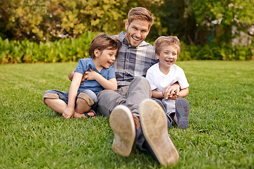 Image showing Smile, nature and portrait of kids with father relaxing on grass in outdoor park or garden. Happy, family and excited boy children sitting on lawn with young dad for bonding in field together.