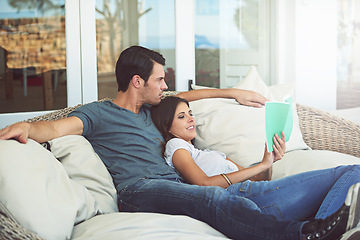 Image showing Couple, relax and book on patio, love and chair to relax and dating on couch for learning. Man, woman and romance while happy, smile and reading for entertainment and together in living room
