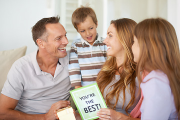 Image showing Mothers day, family and home with children, dad and love together with a note, gift and holiday. Laugh, girl and mom with support and bonding on a living room sofa with a present and card in house