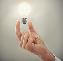 Image showing Hand, light bulb glow and ideas for business growth and development isolated on grey background. Person with insights, corporate innovation and knowledge for enlightenment and inspiration in studio