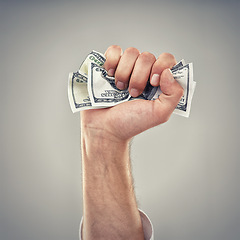 Image showing Closeup, hand and money for finance, greed and capitalism for business on grey background in studio. Fist, cash and dollar to invest, pay or loan for bid opportunity, trading and financial market