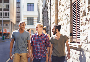 Image showing Male friends, walking and talking in city, smile and conversation on travel holiday. Urban, fun and diverse group of happy men, discussing and bonding while out on stroll in New York on vacation