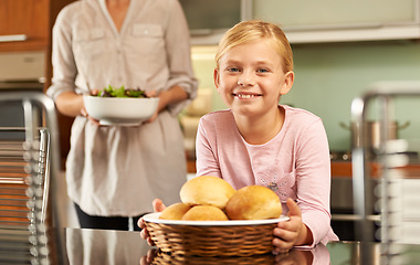 Image showing Girl, portrait and cooking in kitchen with mother, meal and learning for child development in home. Daughter, mommy and food preparation with bread basket for lunch, nutrition and smile for baking