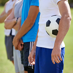 Image showing Field, team and hand holding soccer ball for game, training and competition with fitness. People, group and football player with anthem, captain or leader for sports, exercise or workout for contest