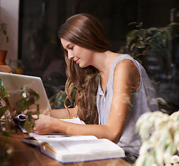 Image showing Student, woman and reading in cafe for study, knowledge and education with notebook, laptop and smile. Young person, learning and research in books for assignment, assessment or exam in coffee shop