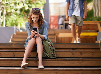 Image showing Phone, education and student woman on steps of university or college campus for social media break. Scholarship, school and study with young person typing mobile text message on stairs at recess