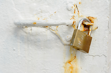 Image showing Weathered padlock on a rust-stained metal latch against a white 