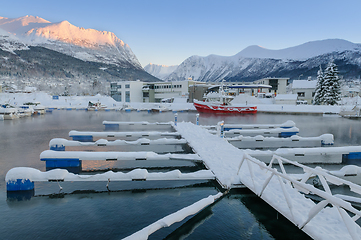 Image showing Winter morning at a snow-covered dock with a red boat in a mount