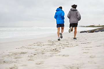 Image showing Rear view, men and running on beach, sand and fitness for wellness and gym wear in cold coast. Male athletes, jog and training for seaside, health and outdoor for sport and exercise together