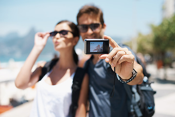 Image showing Happy couple, smile and travel with camera for selfie, sunglasses and backpack outdoor. People, man and woman on adventure for break or holiday, trip and memories in relationship together