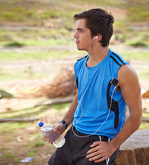 Image showing Athlete, rest and drinking water on run outdoor, running and music while exercising. Nature, forest and workout with bottle for hydration, earphones and motivation or training for trail marathon