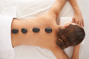 Image showing Hot stone, massage and top view of woman in salon to relax for skincare, beauty or pamper body for wellness at luxury spa. Therapy, above and person with rocks in treatment for back, spine and health