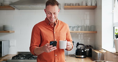Image showing Man, drinking coffee and typing on phone or browsing social media at home, happy and relax on weekend. Male person, communication and mobile app for online conversation, humor and laughing in kitchen