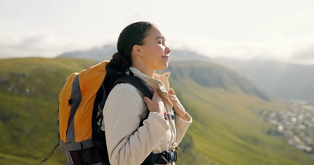 Image showing Young woman, trekking on mountains and breathing fresh air for outdoor wellness, fitness and health. Happy person in wind with backpack and hiking in nature on a hill for adventure, travel or journey