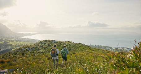 Image showing Back of couple hiking, travel on mountains and walking for adventure, wellness and health in nature and flowers. Sports people with backpack for trekking on rocks, green hill and eco friendly journey