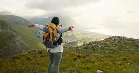 Image showing Woman, mountain top and freedom or celebration of hiking goals, travel or trekking adventure in nature. Back of person or winner in backpack and arms up for success, achievement or excited on a cliff